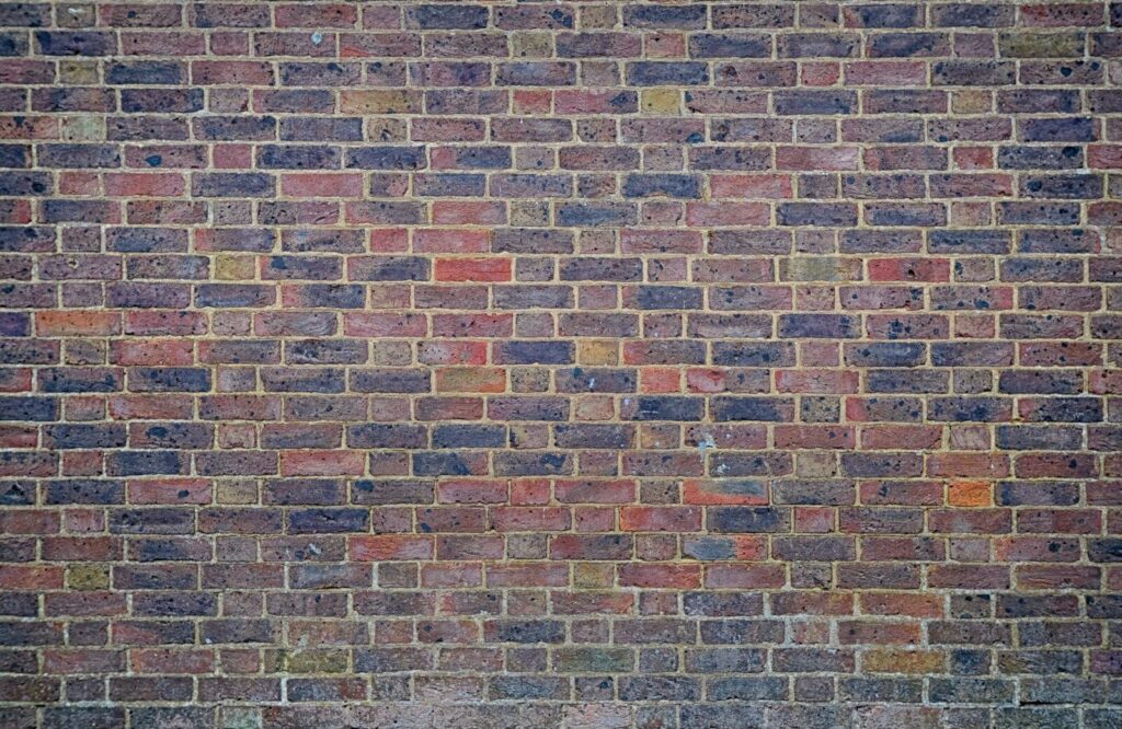 a man sitting on a bench in front of a brick wall